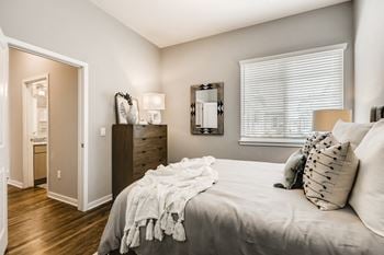 A bedroom with a bed and a dresser and a window